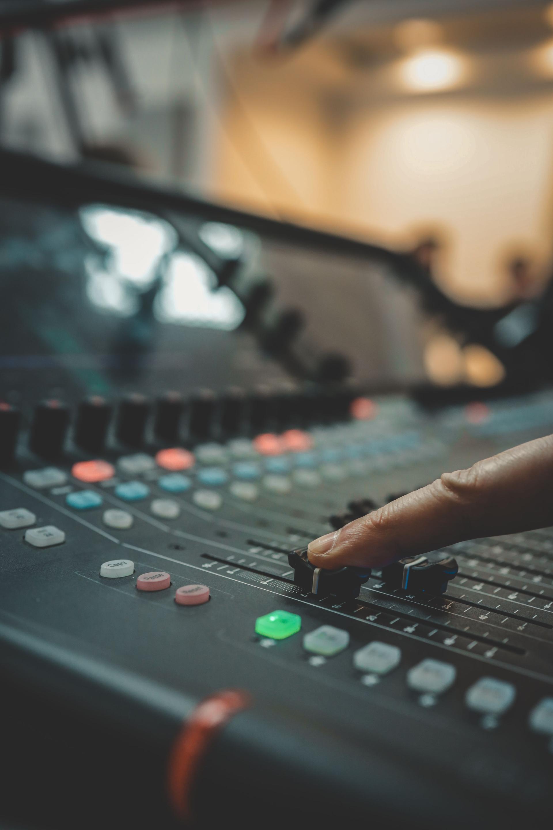 Close-up of a person adjusting sound levels on an audio mixing console during a live event or performance